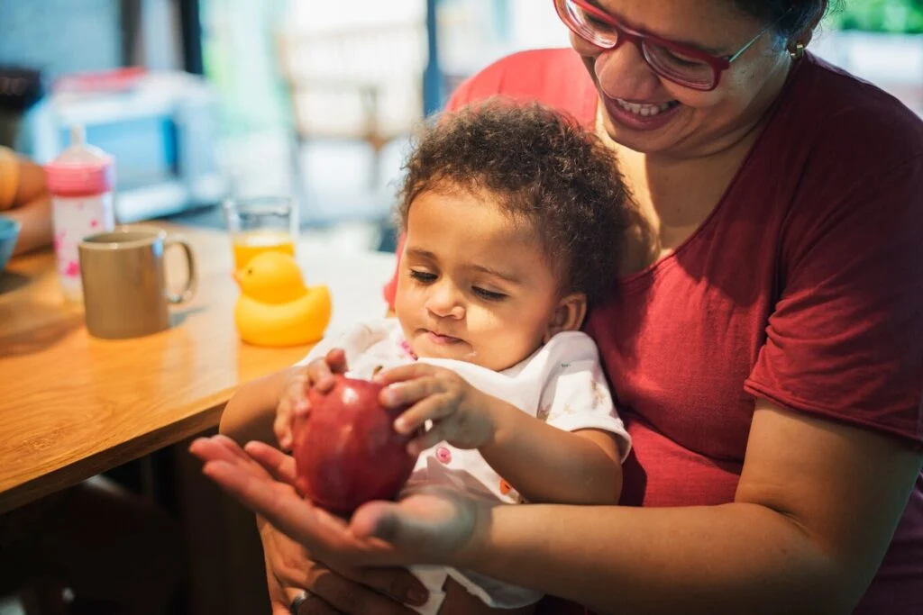 Une maman laisse sa fille jouer avec une pomme