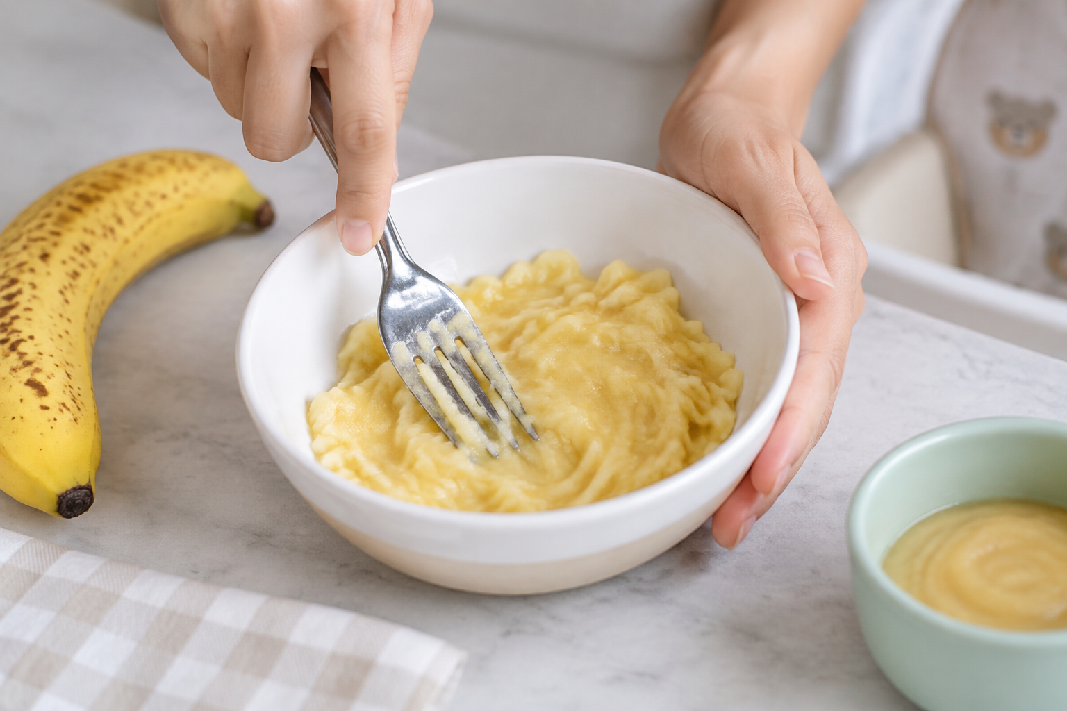 photo blje Purée de banane bien mûre écrasée à la fourchette dans un bol, texture lisse pour bébé.
